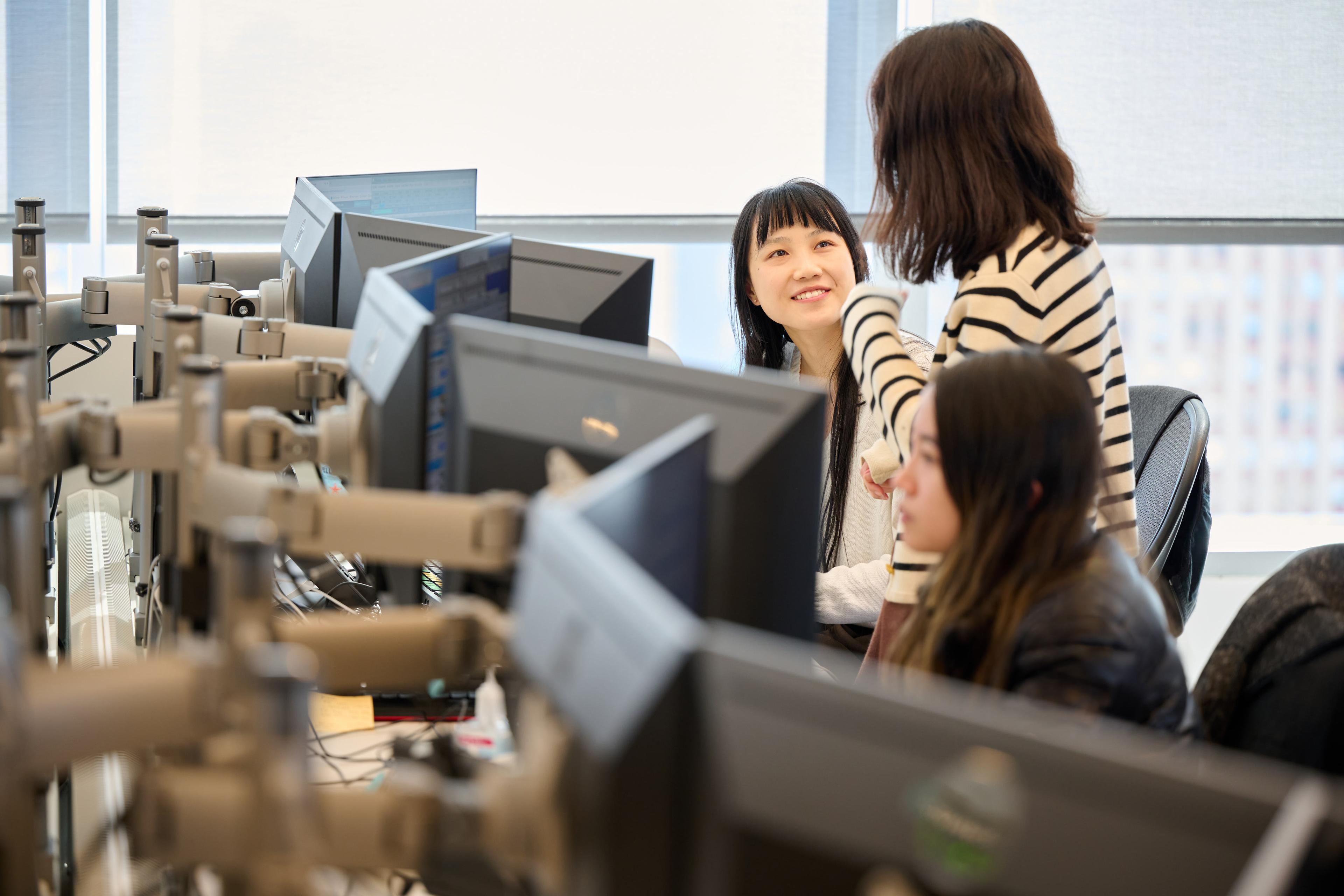 Two women having a discussion in front of a monitor